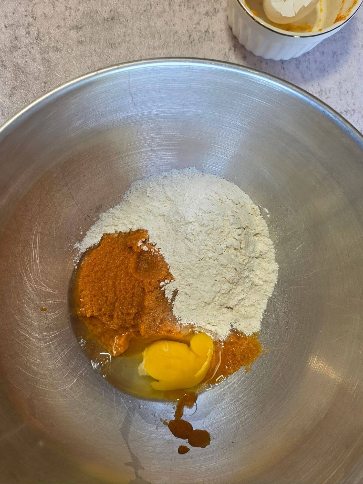 Flour, pumpkin puree and egg in a mixing bowl for making homemade pumpkin pasta dough.