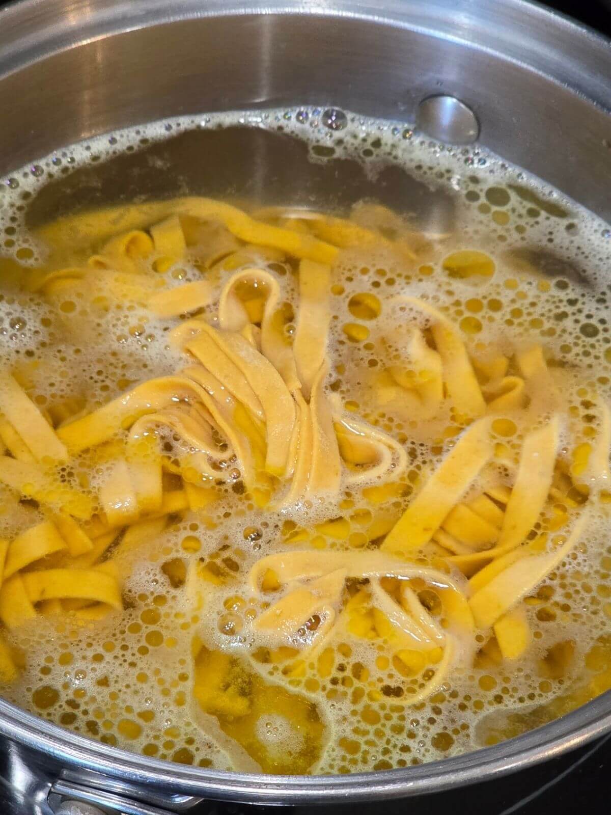 Fresh pumpkin pasta noodles cooking in a pot of boiling water.