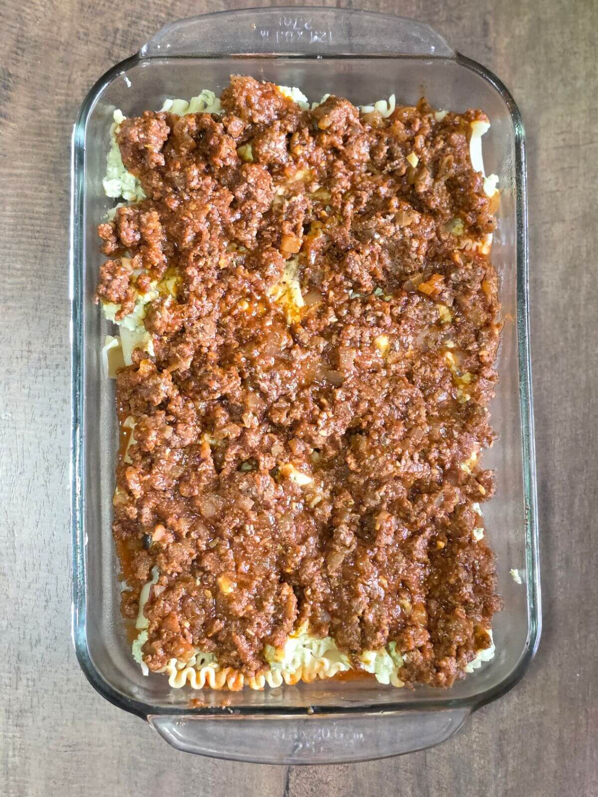 Meat layer on pesto ricotta lasagna. 