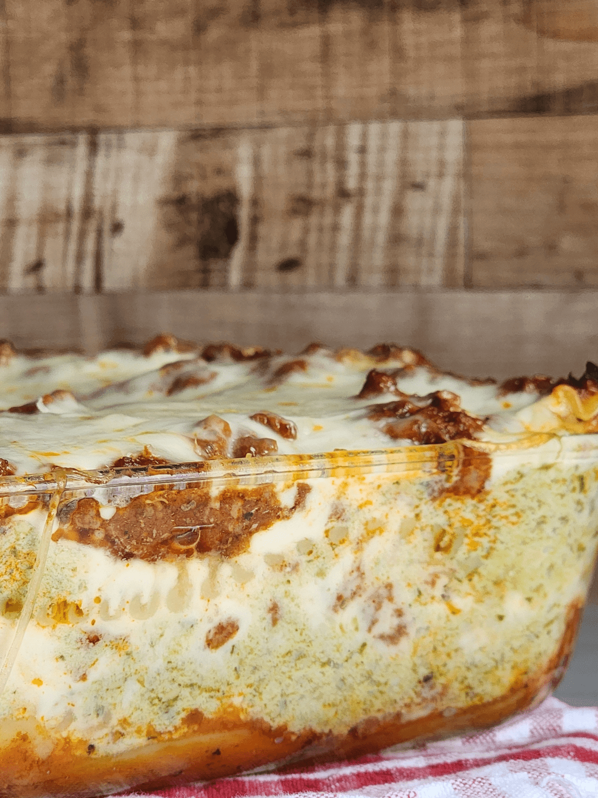 Close up of pesto ricotta lasagna through a clear baking dish. 