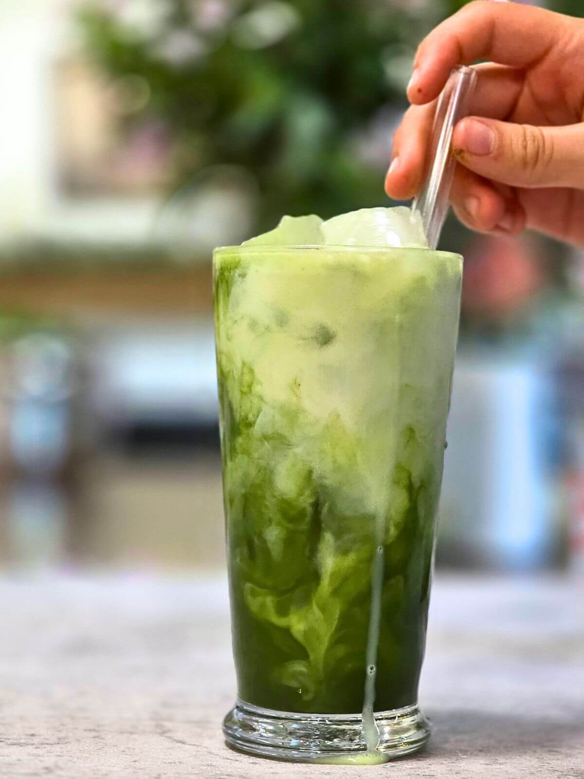 Finished iced matcha latte with creamy cold foam served over ice in a glass.