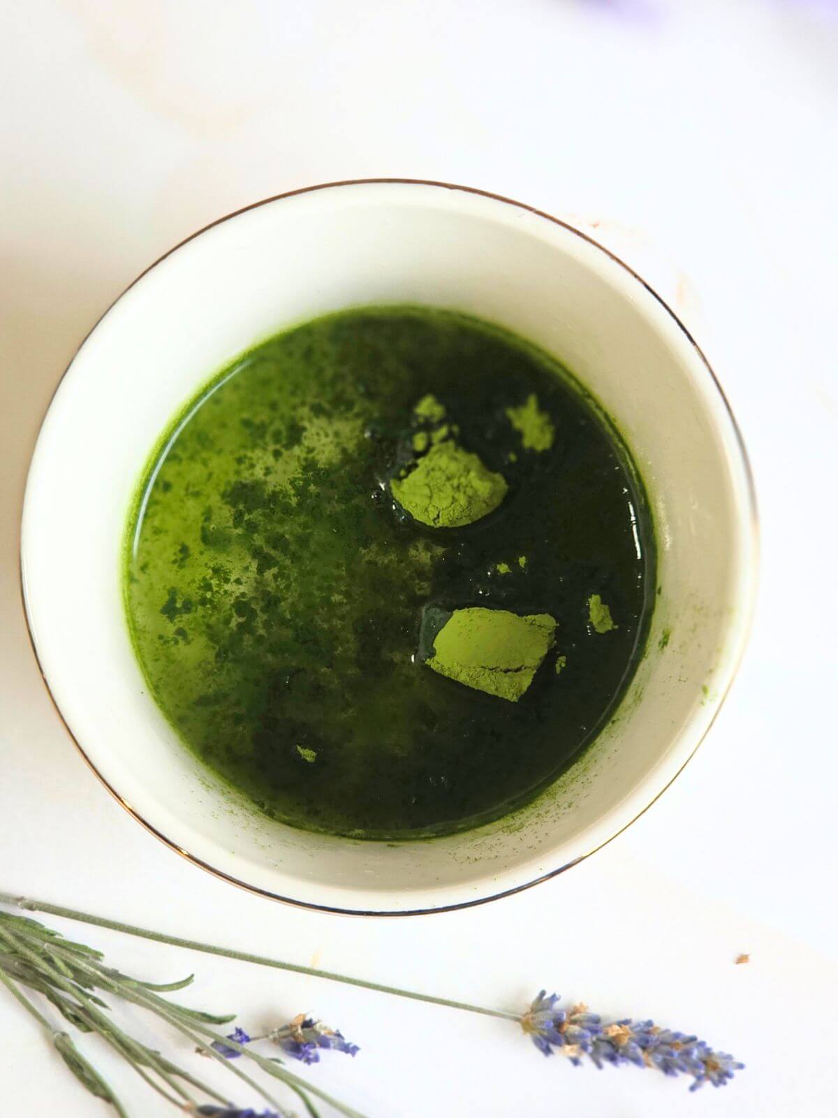 Matcha powder and hot water in a small bowl before whisking for an iced matcha latte.