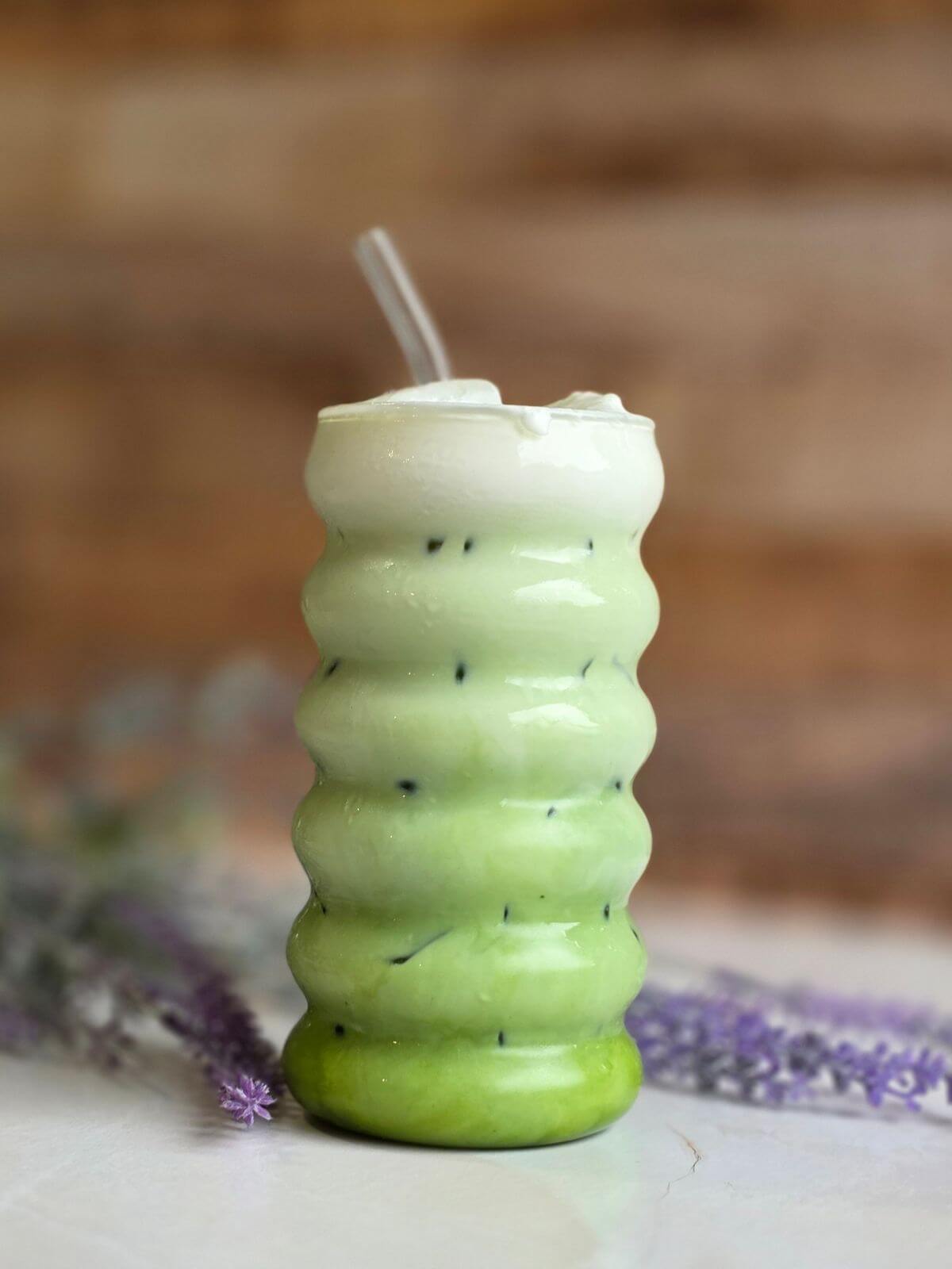 Finished iced matcha latte with creamy cold foam served over ice in a glass.