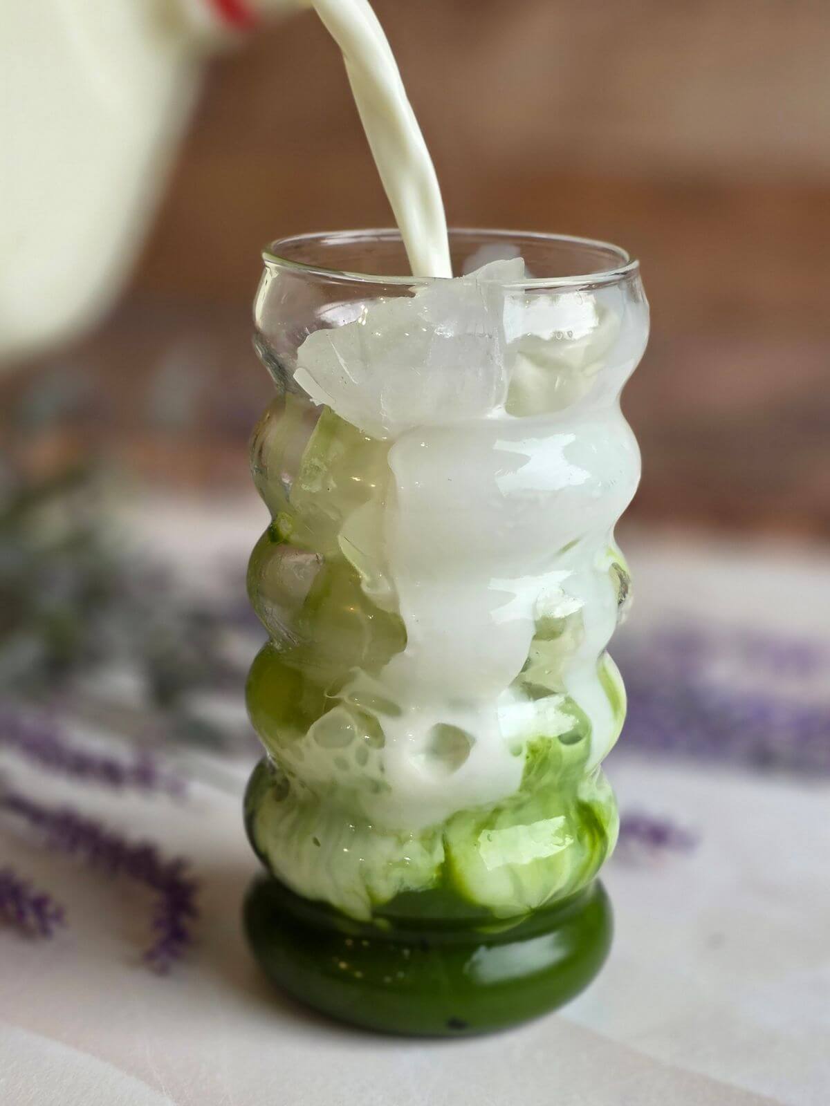 Cold milk being poured over ice and matcha to make an iced matcha latte.
