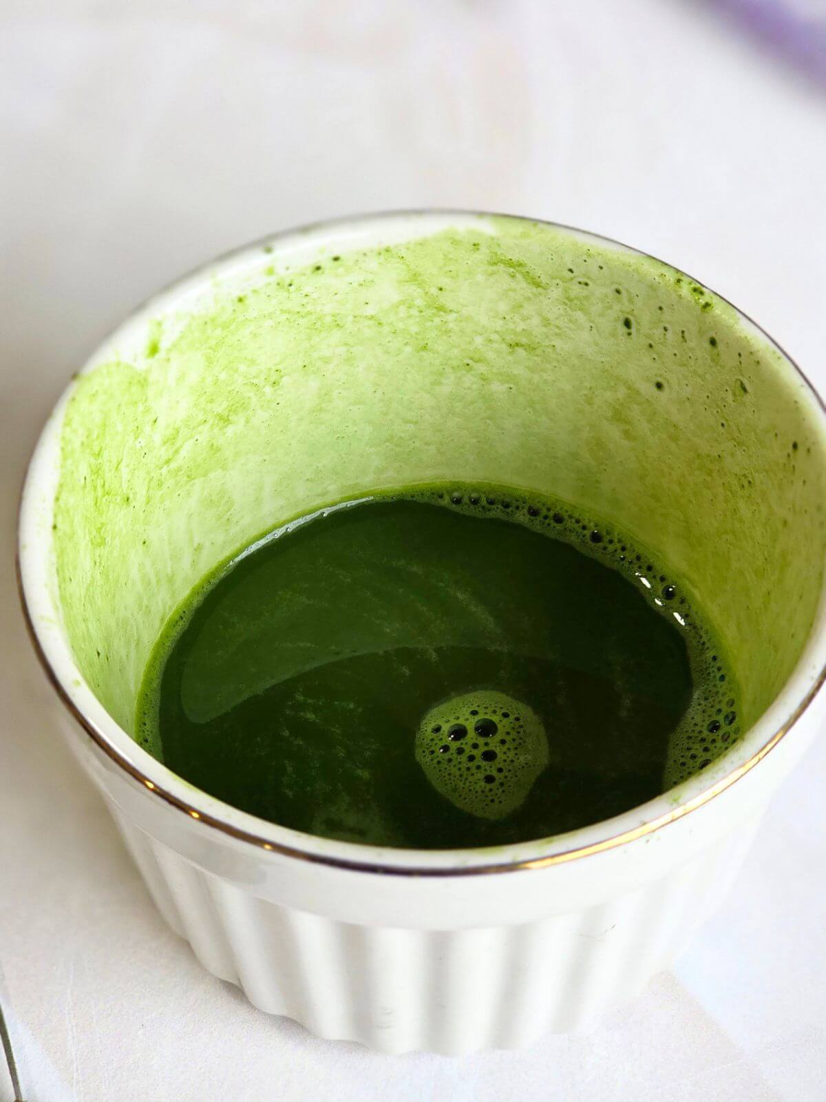 Smooth whisked matcha mixture in a small bowl ready to use in an iced matcha latte.