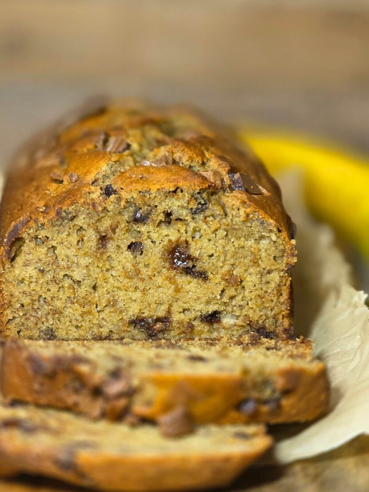 Freshly baked sourdough discard banana bread loaf with chocolate chips and sliced pieces.