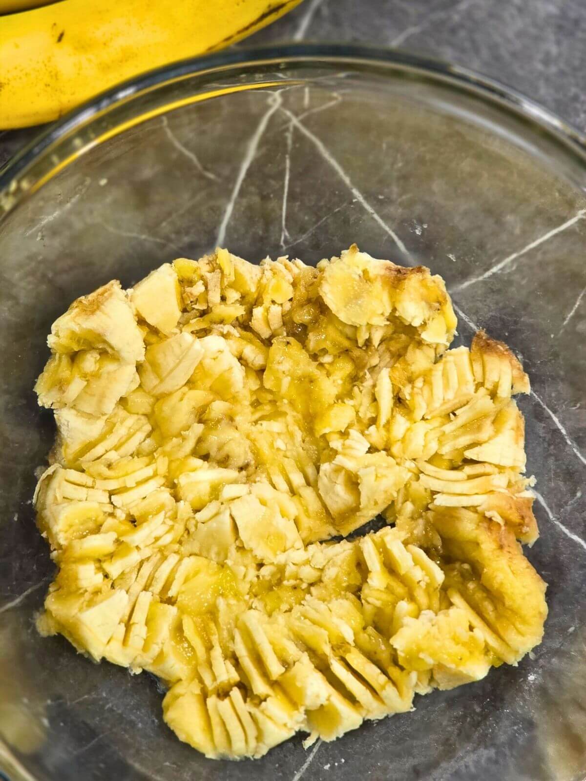 Mashed ripe bananas in a glass bowl for sourdough discard banana bread.